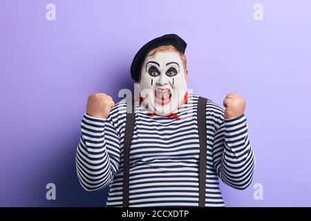cheerful funny plump mime artist gesturing joy with his hands isolated on blue background. happiness, positive feeling and emotion Stock Photo