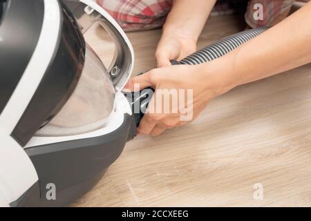 woman disassembles and cleans vacuum cleaner after cleaning use. housekeeping Stock Photo