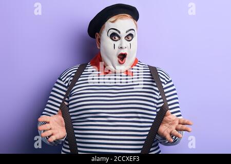 plump performer with painted face posing to the camera. close up portrait, isolated blue background, studio shot.lifestyle. comedy Stock Photo