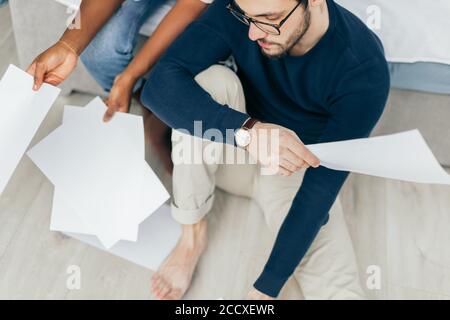 African and Caucasian mixed race married couple sitting on the floor at home checking unpaid bills, taxes, due debt, bank account balance. There is a Stock Photo