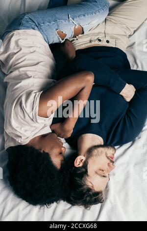 Positive delighted multiethnic couple sleeping together in bed on white sheets, happy traditional family concept. Stock Photo