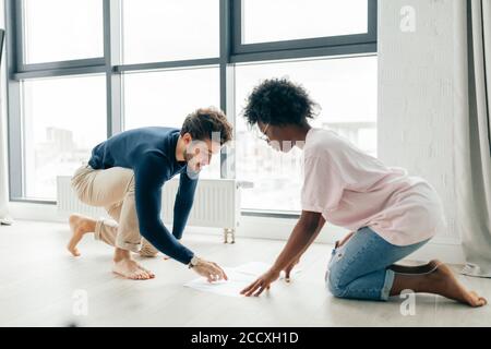 African and Caucasian mixed race married couple sitting on the floor at home checking unpaid bills, taxes, due debt, bank account balance. There is a Stock Photo