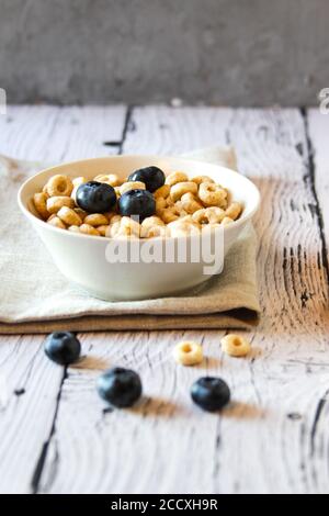 Honey rings with blueberries in a bowl on the table wooden background. Stock Photo
