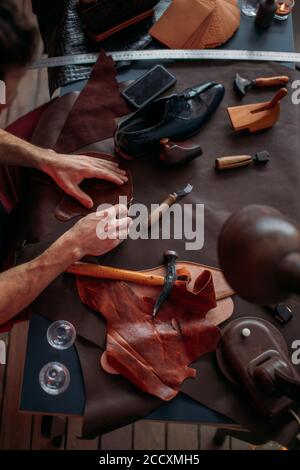 guy working with leather using crafting tool at workshop. close up cropped photo. busy working day Stock Photo
