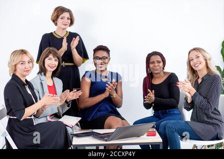 Multi-ethnic colleagues applaud to young woman who has just finished presenting her project. Stock Photo