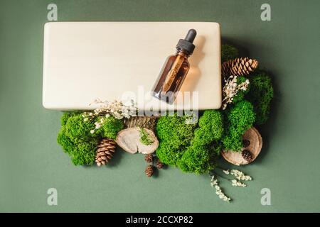 Blank amber glass essential oil bottle on wooden brick. Natural organic cosmetics, herbal essence, sustainable lifestyle concept. Top view, copy space Stock Photo