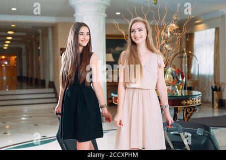 Young girls near reception desk in hotel. Young girls comes to the hotel. Stock Photo