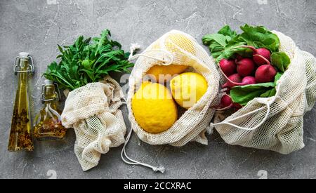 Fresh fruits and vegetables in eco cotton bags on table in the kitchen. Zero waste shopping concept. Stock Photo