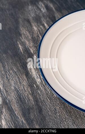 White plate with a blue border on the gray wood artistic plank. Close up Stock Photo