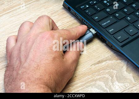 a man's hand inserting a flash card into a laptop connector Stock Photo