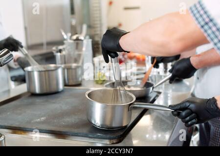 Cooks prepare meals on an electric stove in a professional kitchen in a restaurant or hotel. Stock Photo