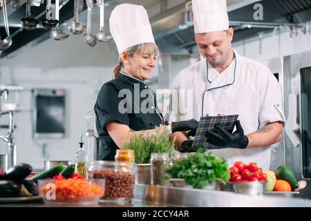 Two chefs discuss the menu in the kitchen of a restaurant or hotel. Stock Photo