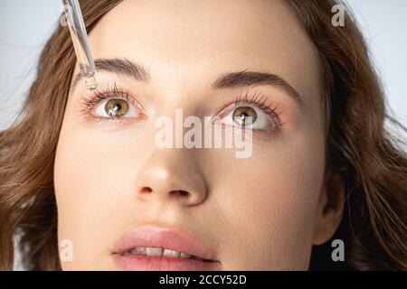 Young dark-haired woman staring at an eyedropper Stock Photo