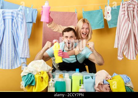 woman and man shouting with happiness, crazy and yelling with raised hands, crazy housekeepers celebrating success. couple found effective washing liq Stock Photo