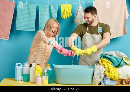 cheerful young family in gloves taking part in the washing contest. close up photo.happiness, joy concept. housework Stock Photo
