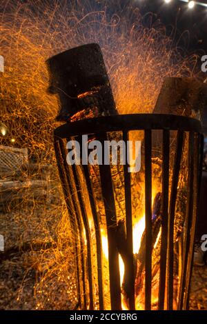 Burning fire pit steel basket in darkness on cold october night in autumn with fire sparks floating around Stock Photo