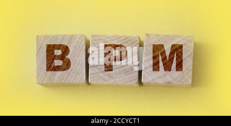 Acronym BPM - Business process management. Wooden small cubes with letters isolated on yellow background. Business Concept image Stock Photo