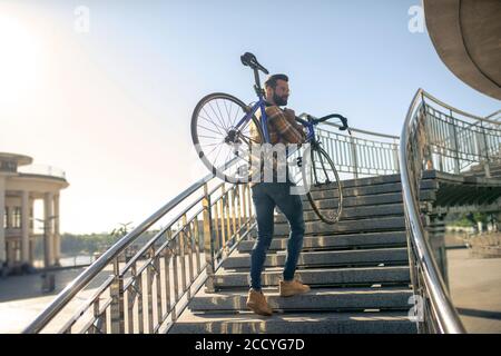 Man climbing stairs with bike in morning Stock Photo
