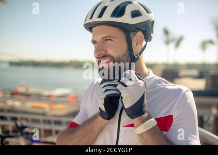 Concentrated man in sports gloves buttoning helmet Stock Photo