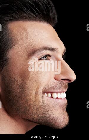 Laughing attractive man in profile in front of black Stock Photo