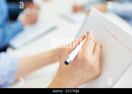 Hand of a businesswoman is making notes in a writing pad Stock Photo