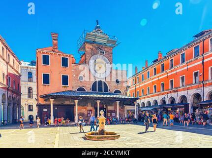 Venice, Italy, September 13, 2019: people tourists walking down Campo San Giacomo di Rialto square with Chiesa church building in historical city centre, blue sky background, Veneto Region Stock Photo