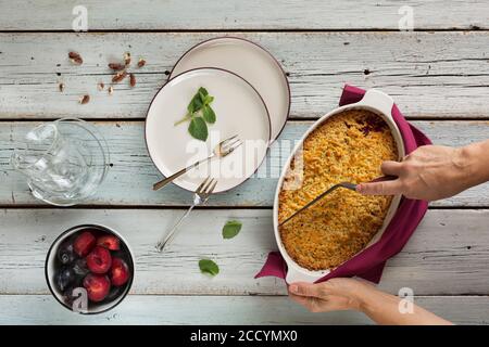 homemade baking grated plum pie with ice cream and nuts on a wooden table served with tea. top view Stock Photo