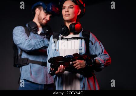Young caucasian man and woman stand isolated on black background, using modern technologies, hi-tech. Virtual reality games Stock Photo