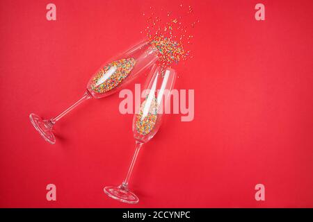 Champagne glass with colorful sugar sprinkles on red background. Stock Photo