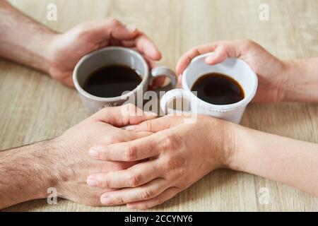 Two hands touch while drinking coffee as a sign of comfort and closeness Stock Photo