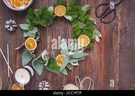 Hand made christmas wreath decorated with dry oranges on wooden table Stock Photo