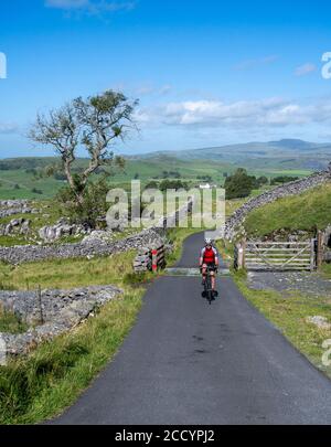 Male cyclist on a quiet lane above Ribblesdale, Yorkshire Dales national park, UK. Stock Photo