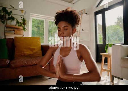 Portrait of young african woman with closed eyes practicing yoga with joint hands