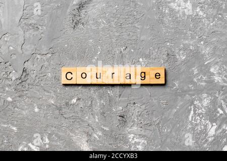 Courage word written on wood block. Courage text on cement table for your desing, concept. Stock Photo