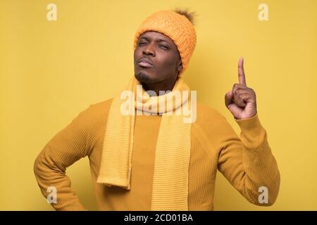 Satisfied african man in swinter clothes showing index fingers up, giving advice Stock Photo