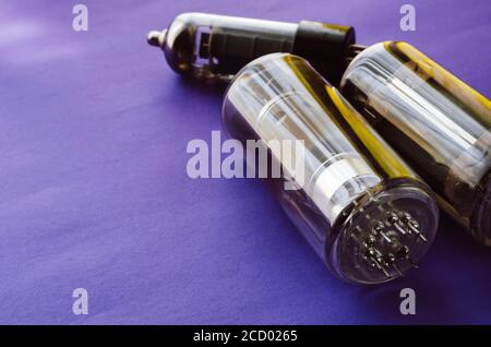 Three random vacuum tubes on a blue background. Outdated radio tubes. Vintage radio parts. Selective focus. Stock Photo