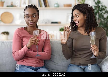 Black woman jealous of her friends engagement ring, drinking champagne