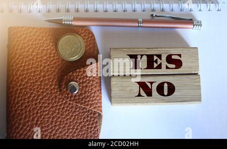 yes and no words on wooden blocks, wallet coins, pen. Business decision concept Stock Photo