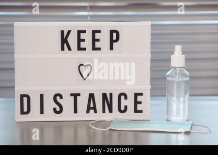 Minimal background image of Keep Distance sign and hand sanitizer on empty workplace desk in post pandemic office, copy space Stock Photo
