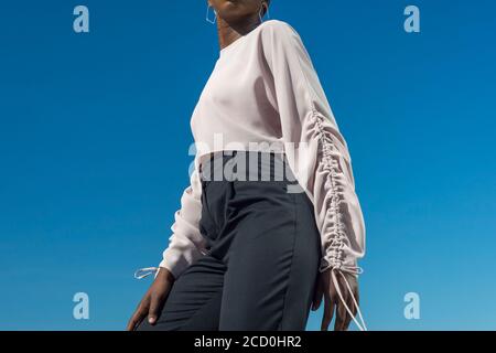 Closeup portrait fashionable dark skinned girl, African girl in a blouse and business pants, posing. Against the background of blue sky. Fashionable b Stock Photo
