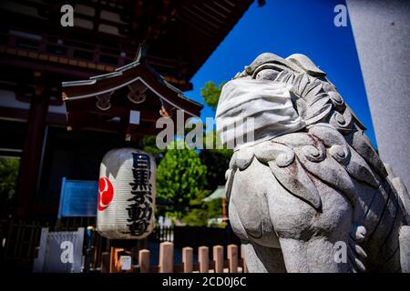 A statue of Guardian dog wearing mask at Meguro fudo temple in Tokyo Stock Photo