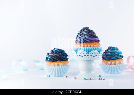 Vanilla cupcakes with galaxy dark whipped cream on light party background with blank space for text Stock Photo