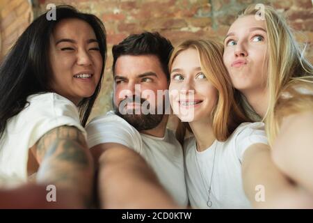 Taking selfie together. Group of adorable multiethnic friends having fun at home. Copyspace. Diversity, inclusion, friendship and love concept. Different nationalities united with sincere emotions. Stock Photo