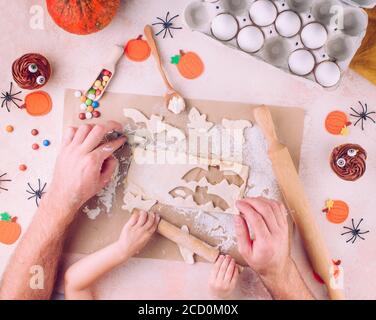 Family holiday activity. Top view of Halloween cookies making by father's and kid's hands. Stock Photo
