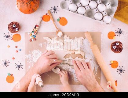 Family holiday activity. Top view of Halloween cookies making by father's and kid's hands. Stock Photo