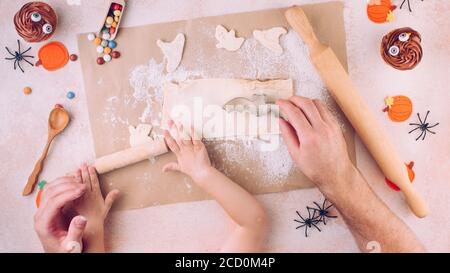 Top view of Halloween cookies carving by father and kid hands. Stock Photo