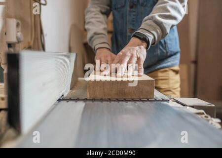Carpenter in the workshop processes wood planks on a grinder Stock Photo