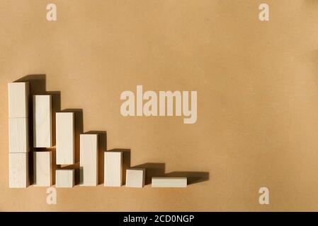 Economic or financial graph from wooden geometric three-dimensional figures - blocks and cubes on a beige background with shadows, copy space. Constru Stock Photo