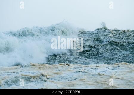 close up of high seas and waves crashing during a storm in Winter with sea foam or spume on the ocean surface which is algal bloom concept weather Stock Photo