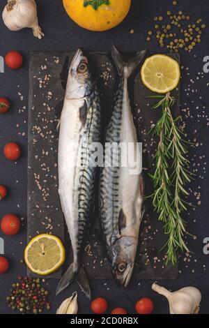 Fresh raw mackerels with salt, garlic, pepper and lemon. Healthy Mediterranean food and dieting concept, top view, flat lay. Stock Photo